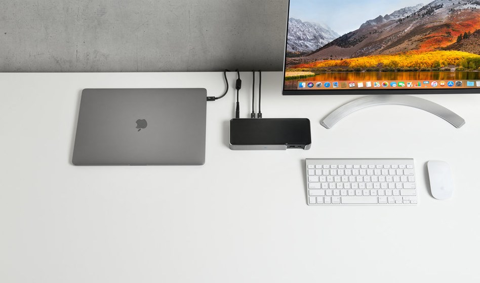 A desk set up with a monitor, keyboard and mouse, a laptop, and a docking station