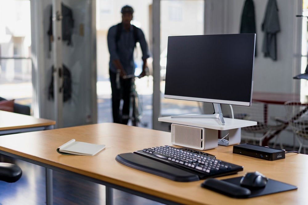 A desktop monitor setup with a Kensington docking station and CoolView Monitor Stand