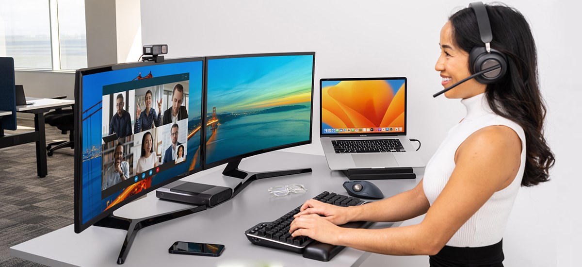 Person working from office using Kensington's silent mechanical keyboard in front of dual monitors.