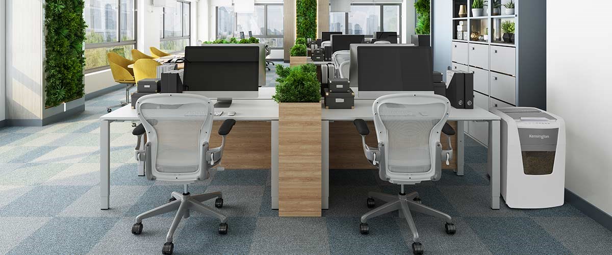 Desks with a Kensington shredder on the side in an eco-friendly office.