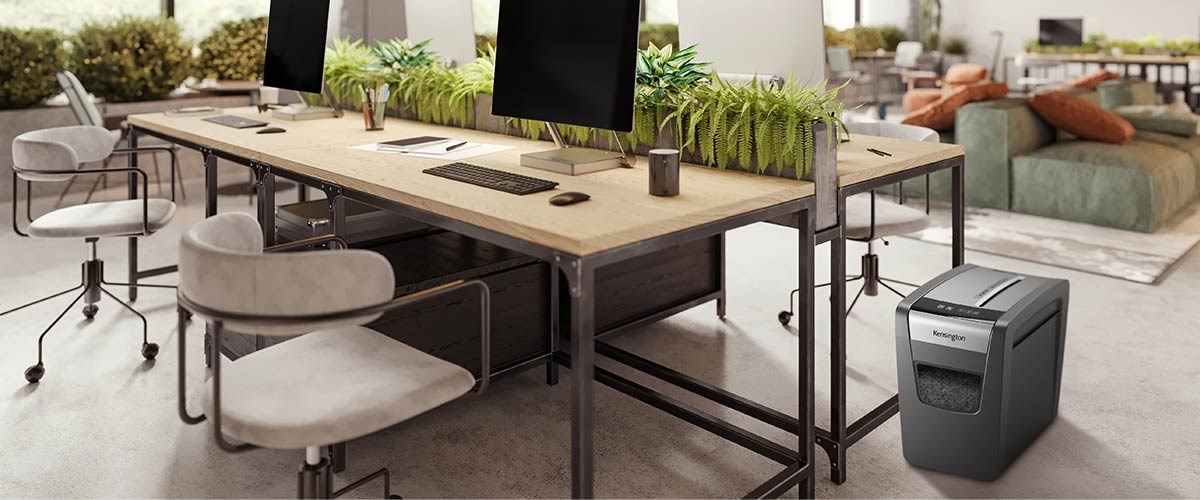 Eco-friendly office surrounded by plants, and a Kensington shredder beside them.