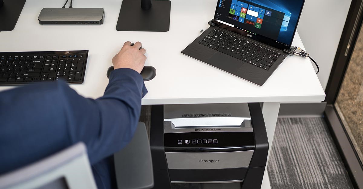 Man sitting working at his desk with a Kensington shredder underneath it.