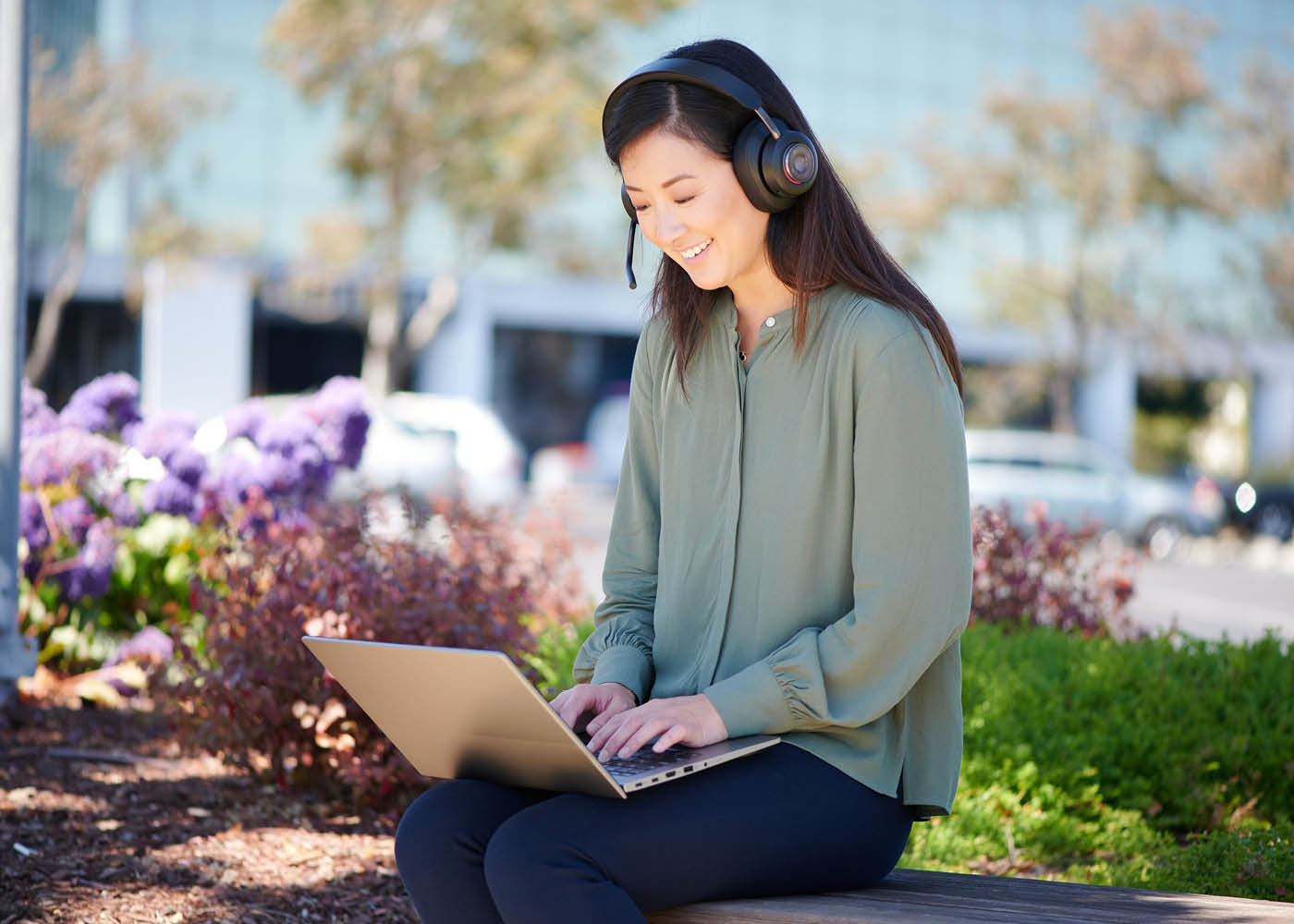 Woman sitting outside working on her laptop while wearing a Kensington H3000 headset