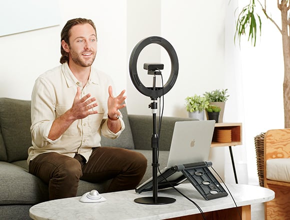 Man standing infront of her desk having a videocall.