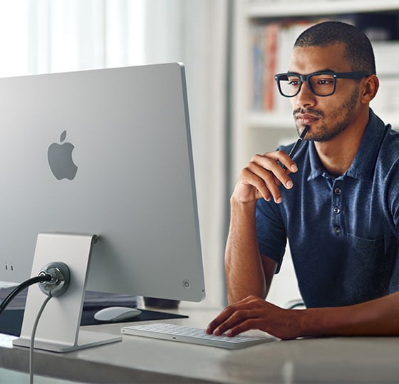 Professional typing at modern workstation with iMac 24inch being secured by a Kensington SafeDome™ Cable Lock.