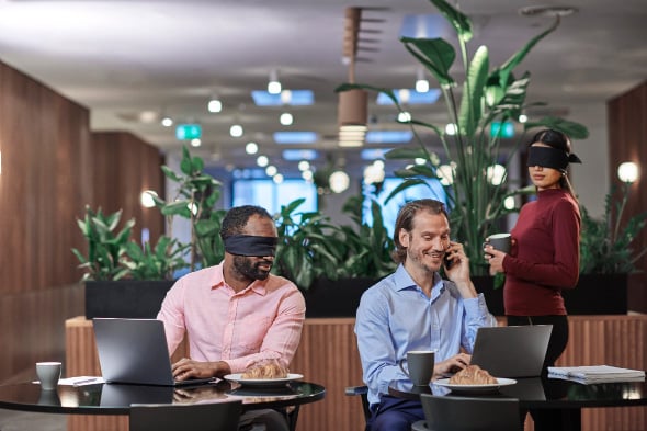 Person looking at camera with others in the background wearing blindfolds