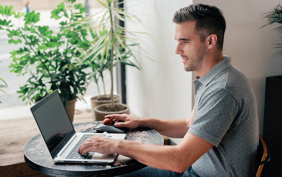 Man working at a cafe using the Slimblade Pro Trackball.