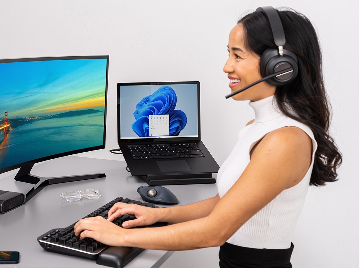 Woman speaking on her headphones and working from home using a Kensington trackball.